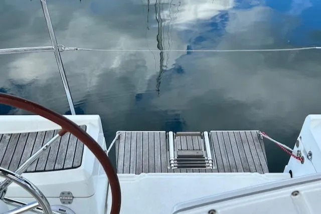 Patience Yacht Photos Pics Jeanneau Sun Odyssey 379 sailboat deck with wooden steps, reflecting sky on water, 2012 model.