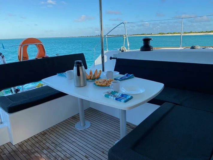 Blue Osprey Yacht Photos Pics Lagoon 450S yacht deck with dining setup, ocean view, and clear blue sky.