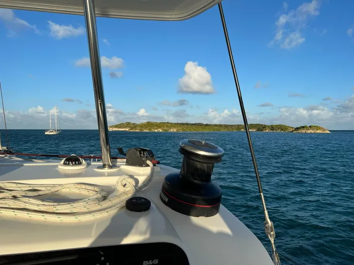 Blue Osprey Yacht Photos Pics Lagoon 450S sailing near an island under a clear blue sky, 2020 model.