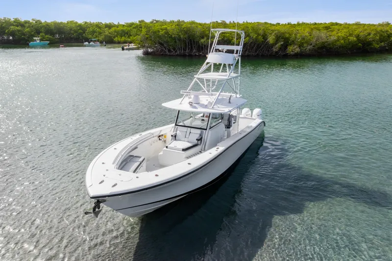  Yacht Photos Pics 2018 Yellowfin 42 Offshore boat on calm water near lush green shoreline.