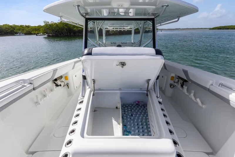  Yacht Photos Pics 2018 Yellowfin 42 Offshore boat with open storage compartment, filled with water bottles, on a calm waterway.