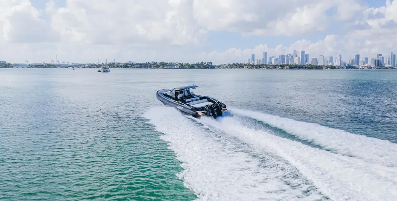 Heavy D Yacht Photos Pics 2023 Pirelli Tecnorib 50 speeding on open water with city skyline in background.