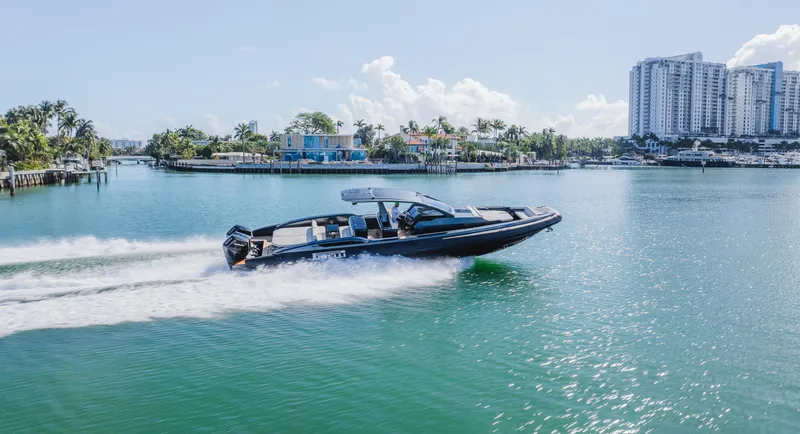 Heavy D Yacht Photos Pics 2023 Pirelli Tecnorib 50 speedboat cruising on a sunny waterfront with cityscape background.