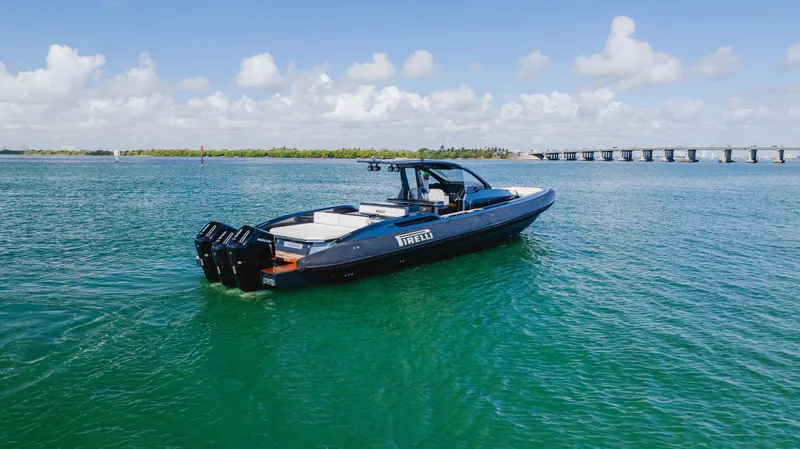 Heavy D Yacht Photos Pics 2023 Pirelli Tecnorib 50 boat on clear blue water, bridge in background.