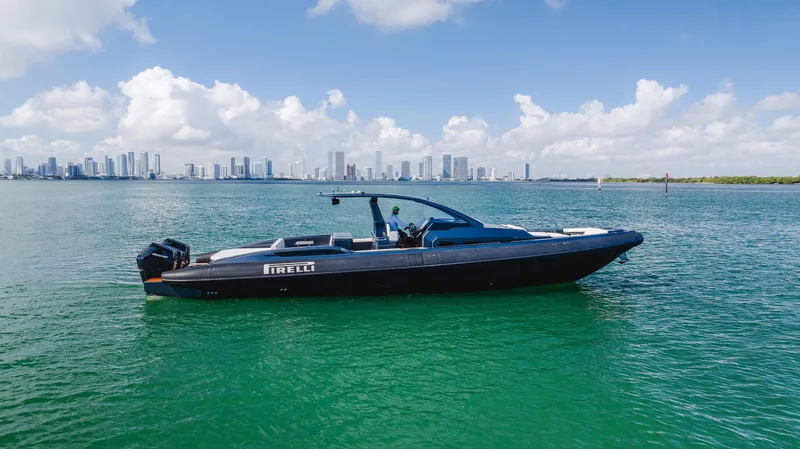 Heavy D Yacht Photos Pics 2023 Pirelli Tecnorib 50 boat on calm water with city skyline in background.