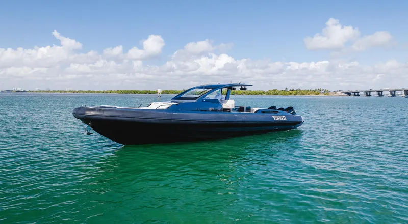 Heavy D Yacht Photos Pics 2023 Pirelli Tecnorib 50 boat on calm water under blue sky.