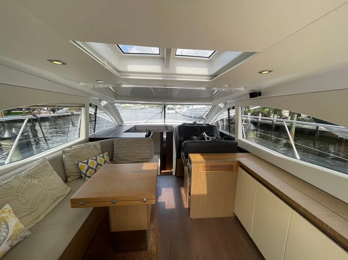 Oasis Yacht Photos Pics Interior of 2014 Beneteau Gran Turismo 49 yacht with seating and helm, docked by water.