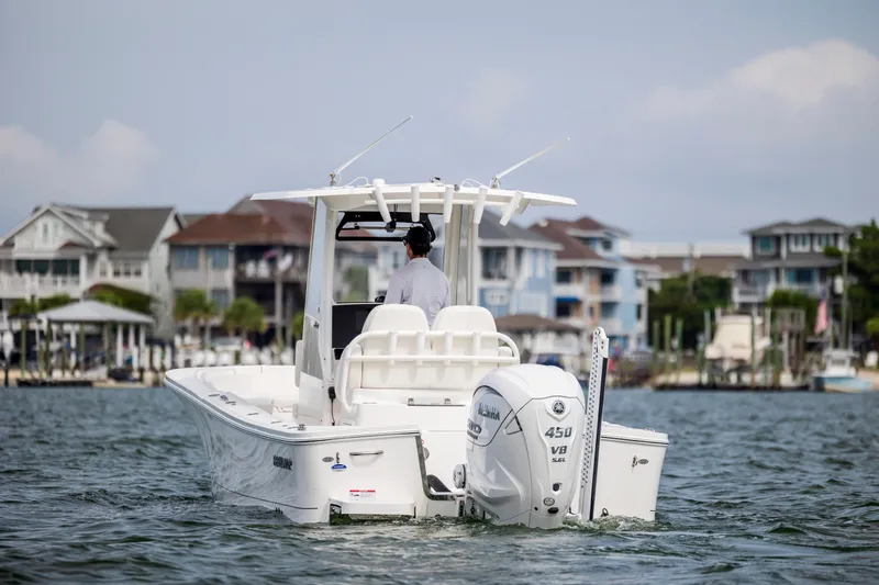  Yacht Photos Pics 2024 Regulator 26XO boat cruising near waterfront homes, featuring a powerful Yamaha 450 V8 engine.