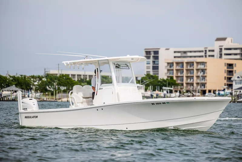  Yacht Photos Pics 2024 Regulator 26XO boat cruising on water near coastal buildings.