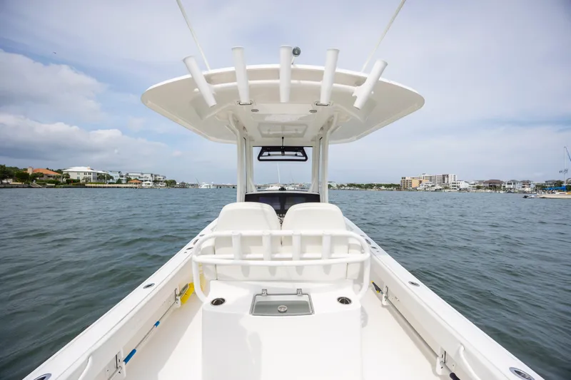  Yacht Photos Pics 2024 Regulator 26XO boat on water, showcasing helm and seating, with coastal background.