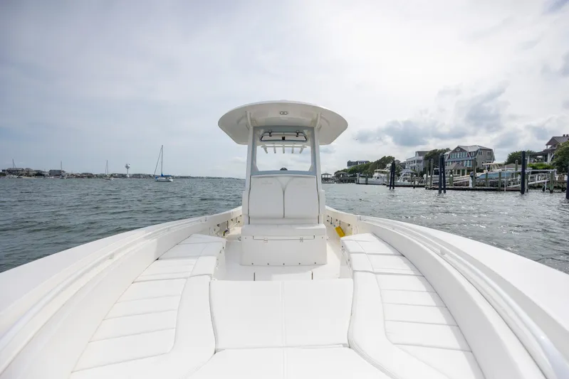 Yacht Photos Pics 2024 Regulator 26XO boat on calm waters near a coastal neighborhood.