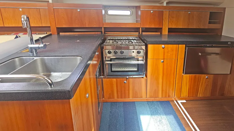 Acadia Yacht Photos Pics Modern kitchen interior of 2016 Hanse 415 yacht with wooden cabinetry and stainless steel appliances.