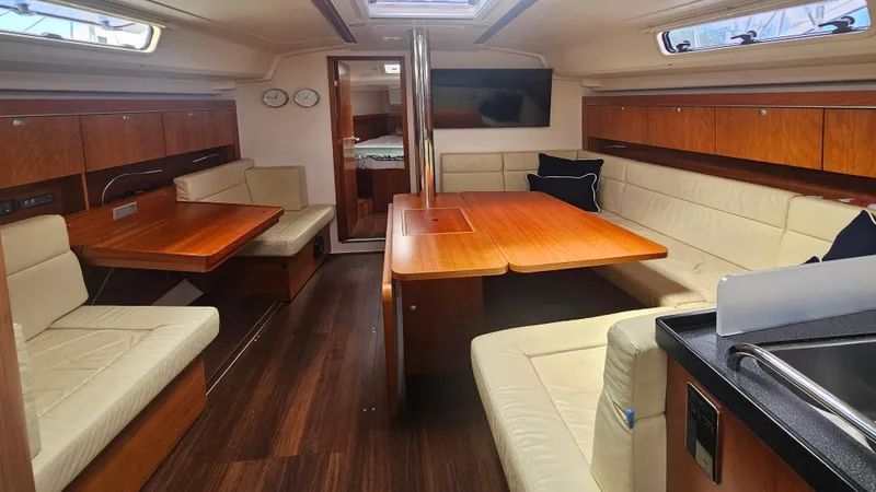 Acadia Yacht Photos Pics Interior of a 2016 Hanse 415 yacht with wooden furnishings and beige seating.