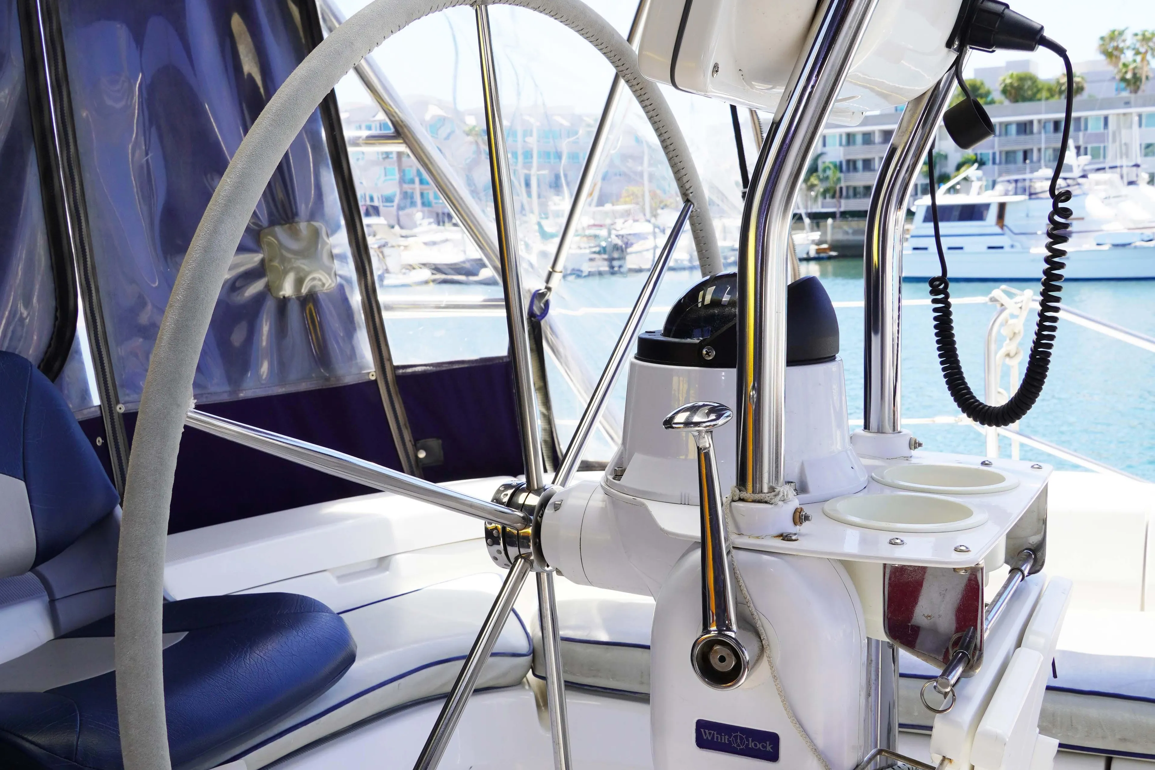 Steering wheel of 2000 Hunter Passage 420 yacht with marina background.