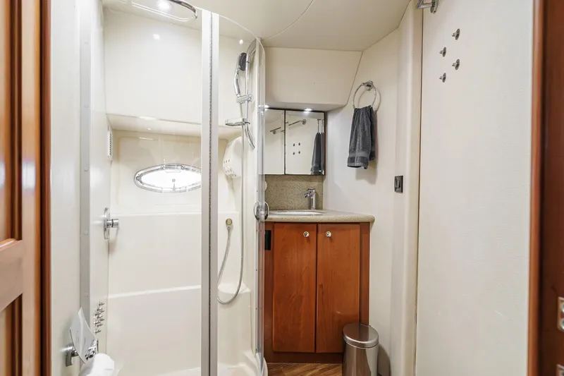 Nauti Pops Yacht Photos Pics 2007 Silverton Convertible yacht bathroom with shower, sink, and wooden cabinetry.