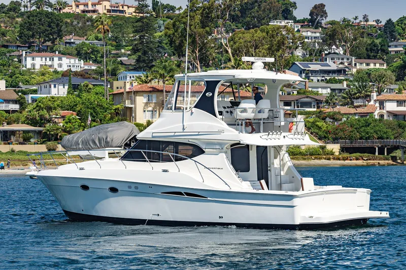 Nauti Pops Yacht Photos Pics 2007 Silverton Convertible yacht cruising near a scenic coastal neighborhood.