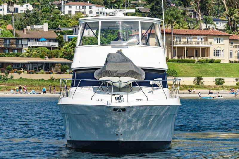 Nauti Pops Yacht Photos Pics 2007 Silverton Convertible yacht on water with beachfront homes in background.