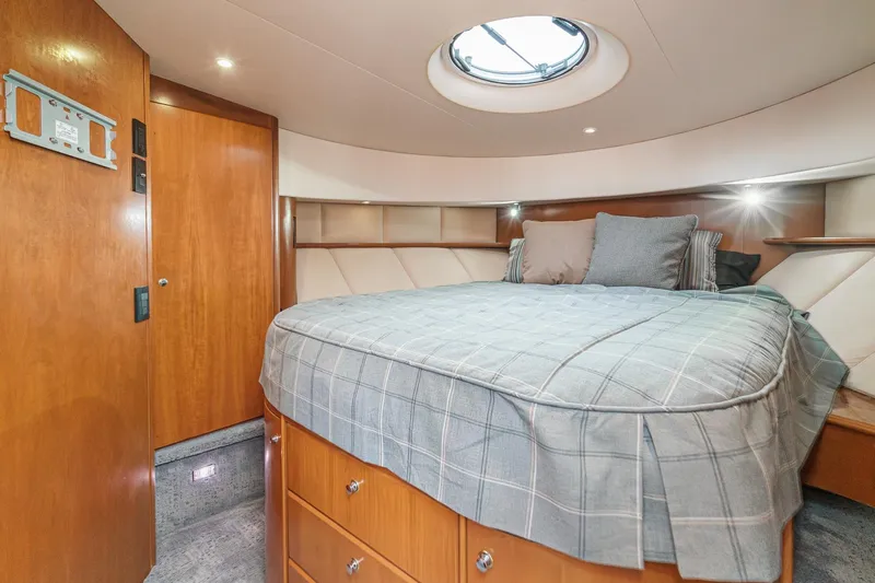Nauti Pops Yacht Photos Pics 2007 Silverton Convertible yacht bedroom with circular skylight and wooden cabinetry.