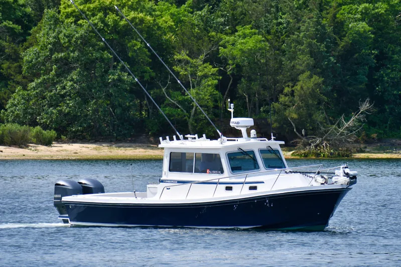  Yacht Photos Pics 2021 Steiger Craft 31 Chesapeake boat cruising on a calm lake with lush green trees.