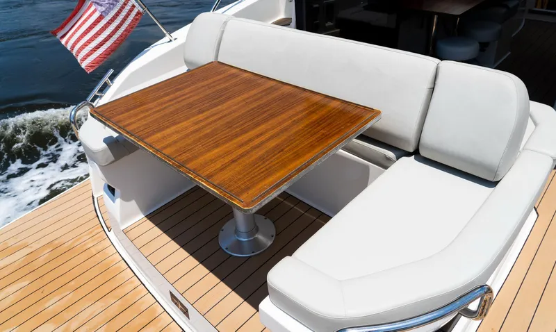 Yacht Photos Pics Luxury seating area on 2022 Bavaria SR41 yacht with wooden table and American flag.