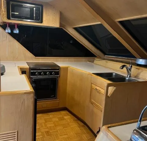  Yacht Photos Pics 1989 Ocean Alexander 42 yacht kitchen with wood cabinetry, stove, microwave, and sink.