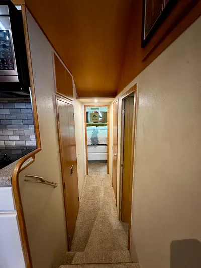 Billie Jo Yacht Photos Pics Interior hallway of 1994 Hatteras 46 Convertible yacht, featuring wood paneling and carpeted flooring.