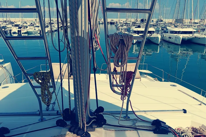  Yacht Photos Pics Bali Catamarans 4.8 (2021) docked in a marina, surrounded by sailboats and clear blue water.