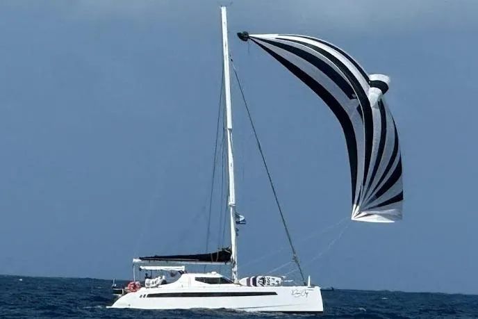Pure Joy Yacht Photos Pics 2023 Seawind 1600 Passagemaker sailing with striped spinnaker on open sea.