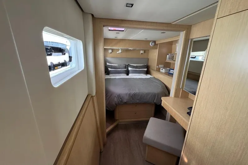 Pure Joy Yacht Photos Pics 2023 Seawind 1600 Passagemaker cabin interior with bed, window, and wooden furnishings.