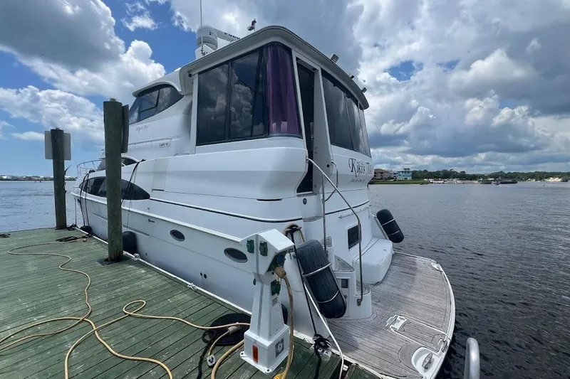 Kiki's Tiki Yacht Photos Pics 2000 Carver 506 Motor Yacht docked by a scenic waterfront under a cloudy sky.