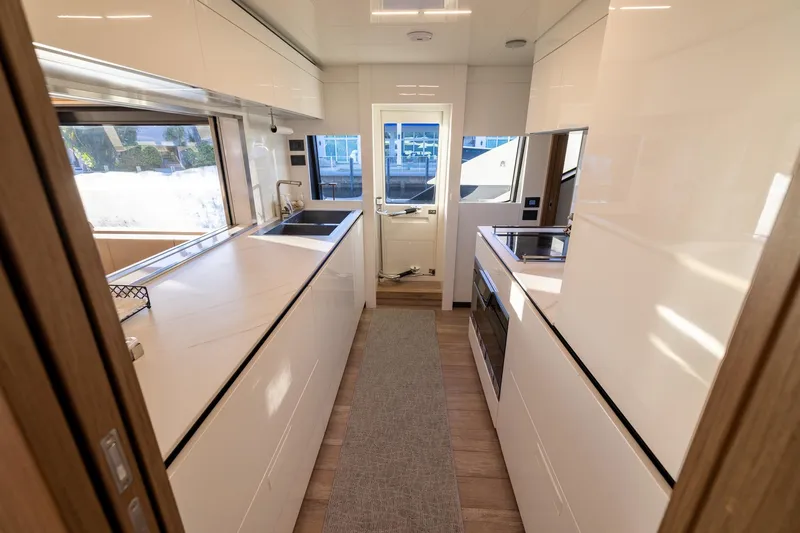 Life: For Sale Yacht Photos Pics Modern kitchen interior of 2021 Ferretti Yachts 920, featuring sleek white cabinetry and appliances.