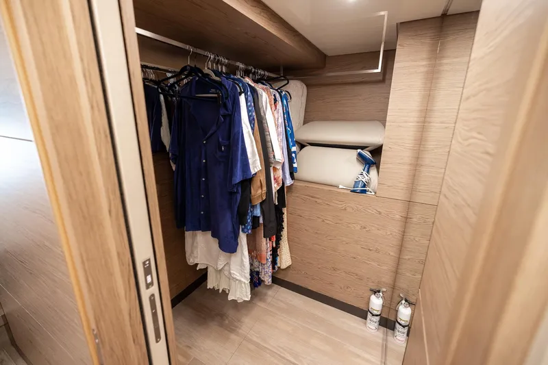 Life: For Sale Yacht Photos Pics Walk-in closet on 2021 Ferretti Yachts 920, featuring hanging clothes and storage shelves.
