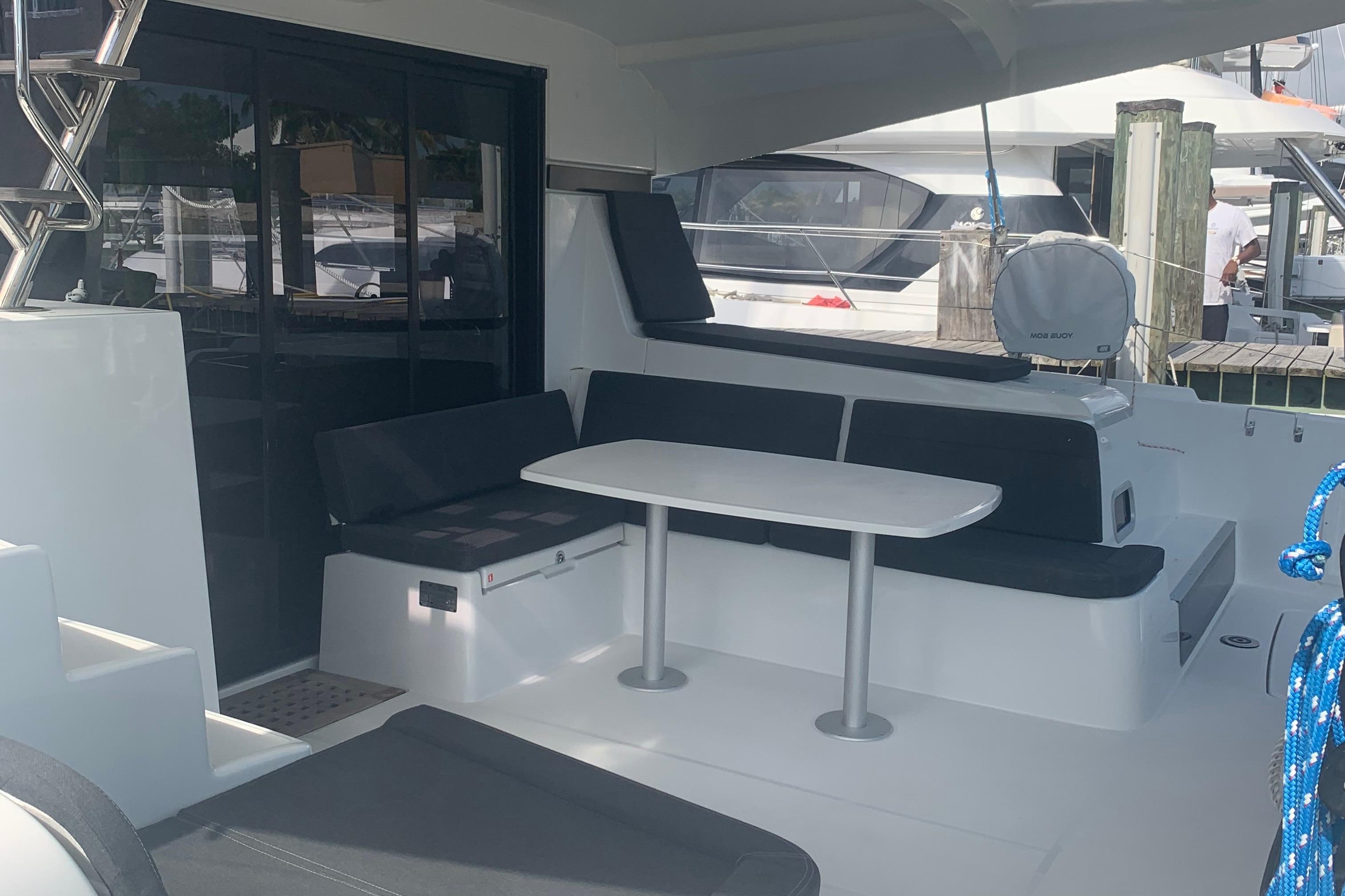 Outdoor seating area on a 2019 Lagoon 42 catamaran with table and cushions.