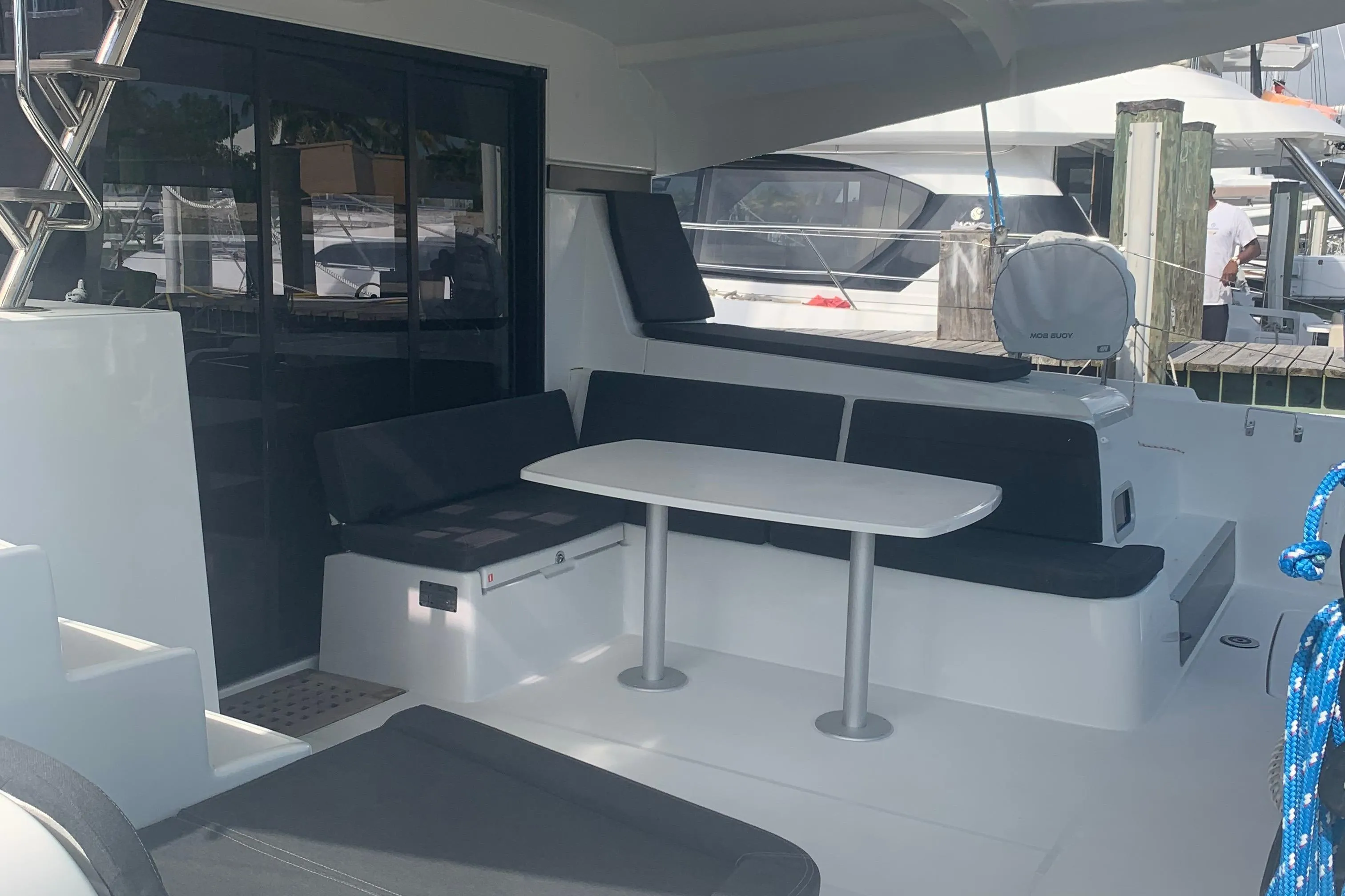Outdoor seating area on a 2019 Lagoon 42 catamaran with table and cushions.