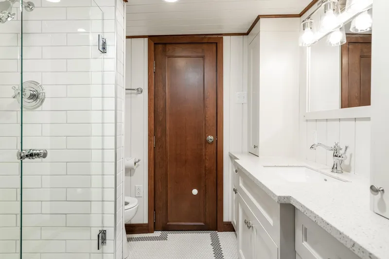 Anne S Pierce Yacht Photos Pics Modern ship bathroom with white tiles, wooden door, and sleek fixtures on Glovertown Shipyard Exploration Ship, 1982.