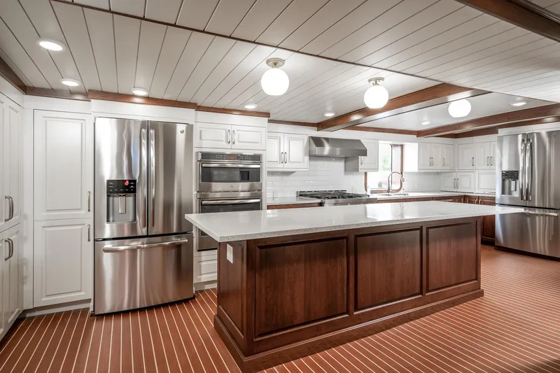 Anne S Pierce Yacht Photos Pics Modern ship kitchen with stainless steel appliances, wood accents, and spacious island.