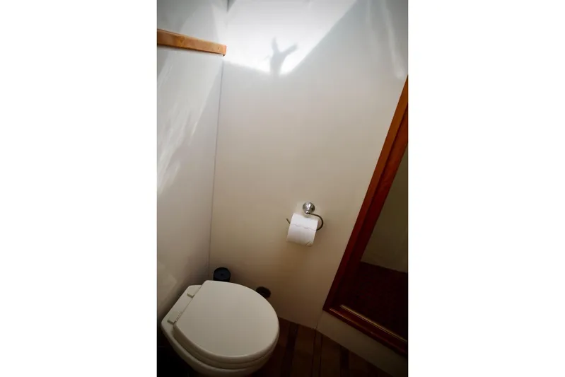 The Donut Hull Yacht Photos Pics Bathroom interior of 2002 Mikelson 50 Sportfisher yacht, featuring toilet and wooden accents.