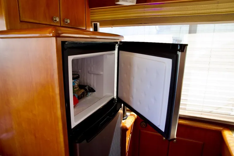 The Donut Hull Yacht Photos Pics Open freezer in 2002 Mikelson 50 Sportfisher yacht interior, wooden cabinetry visible.