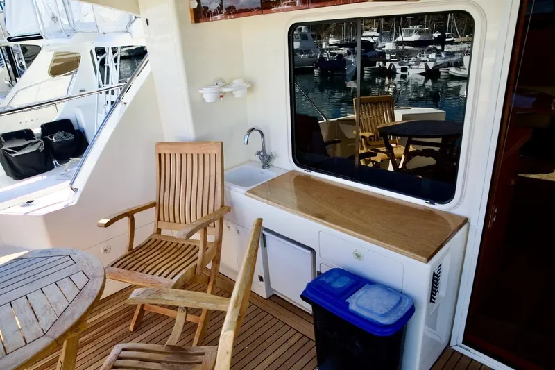 The Donut Hull Yacht Photos Pics Outdoor seating area on 2002 Mikelson 50 Sportfisher yacht with wooden chairs and table.