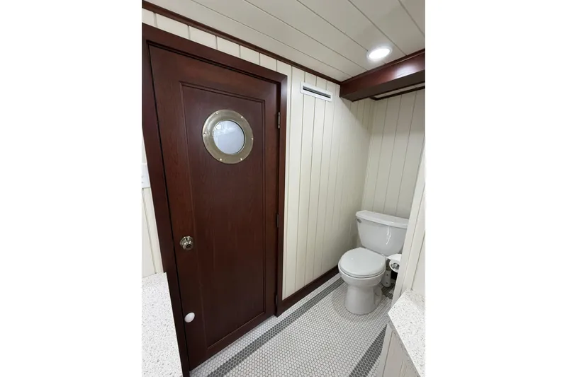 Anne S Pierce Yacht Photos Pics Nautical-themed bathroom with porthole door, white paneling, and modern toilet, Custom Glovertown Shipyard 2021.