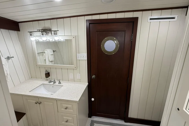 Anne S Pierce Yacht Photos Pics Elegant ship bathroom with porthole door, modern vanity, and bright lighting. Custom Glovertown Shipyard, 2021.