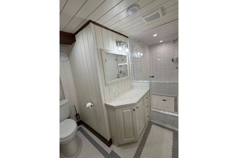 Anne S Pierce Yacht Photos Pics Elegant bathroom with white subway tiles, custom vanity, and glass shower in Glovertown Shipyard model.