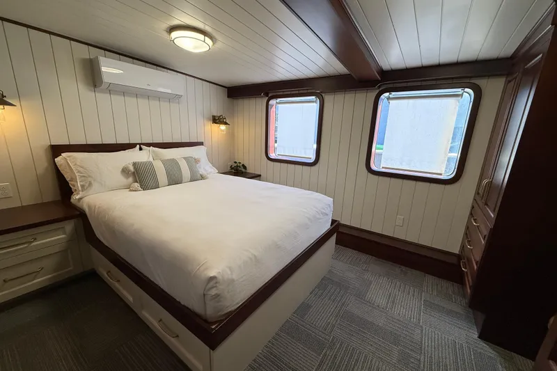 Anne S Pierce Yacht Photos Pics Cozy ship cabin bedroom with white bedding, wooden accents, and two windows, Glovertown Shipyard 2021.