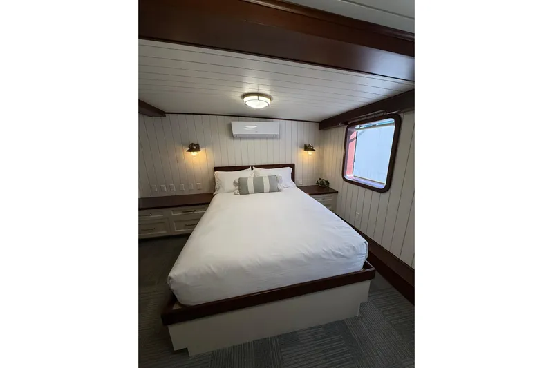 Anne S Pierce Yacht Photos Pics Cozy ship cabin with a neatly made bed, wooden accents, and a window view. Custom Glovertown Shipyard 2021.