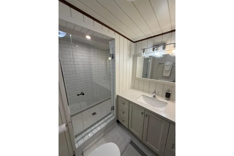 Anne S Pierce Yacht Photos Pics Modern bathroom with glass shower, white subway tiles, and sleek vanity in a 2021 Glovertown Shipyard model.