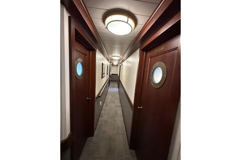 Anne S Pierce Yacht Photos Pics Narrow ship corridor with wooden doors and porthole windows, Glovertown Shipyard 2021 design.