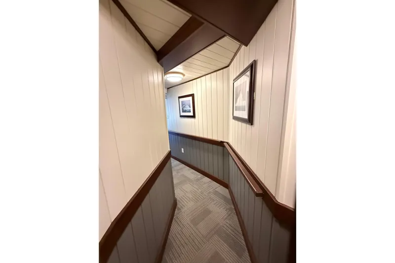 Anne S Pierce Yacht Photos Pics Narrow ship corridor with wood paneling, framed pictures, and carpeted floor, Glovertown Shipyard 2021.