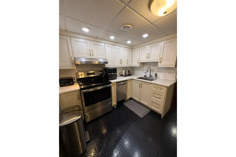 Anne S Pierce Yacht Photos Pics Modern kitchen with stainless steel appliances, white cabinets, and black flooring, 2021 Glovertown Shipyard.