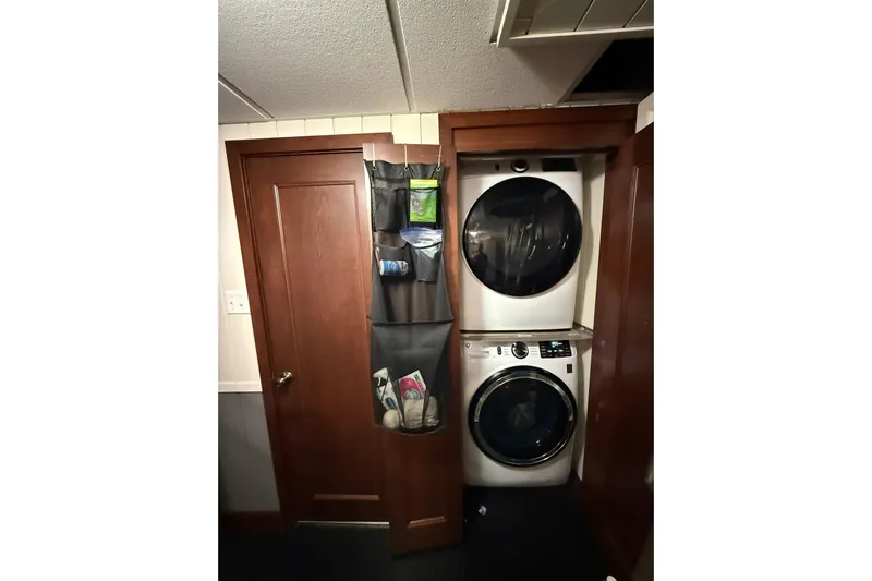 Anne S Pierce Yacht Photos Pics Laundry room with stacked washer and dryer, wooden door, and hanging organizer.
