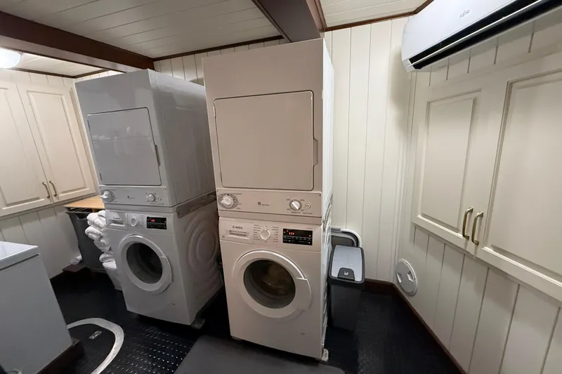 Anne S Pierce Yacht Photos Pics Laundry room with stacked washers and dryers, custom cabinetry, and air conditioning unit.